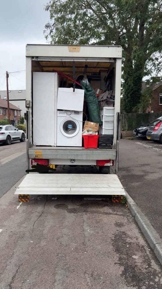 A tail-lift van with its lift lowered, loaded with a washing machine, fridge freezers and crates